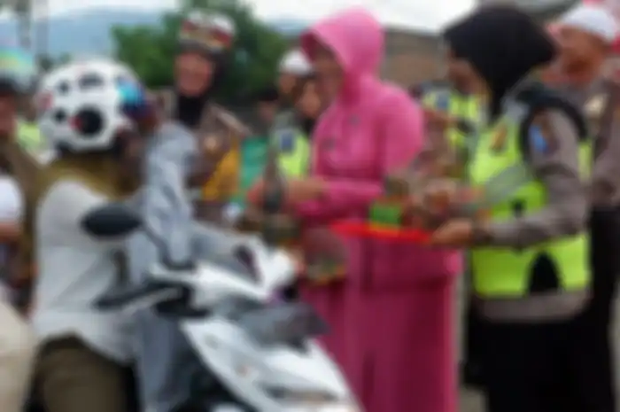 Kasat Lantas AKP Vifa didampingi Ketua Bhayangkari Cabang Aceh Besar memberikan takjil kepada pengguna jalan di Jalan Banda Aceh-Medan, Simpang Aneuk Galong, Besar, Selasa (28/5/2019).