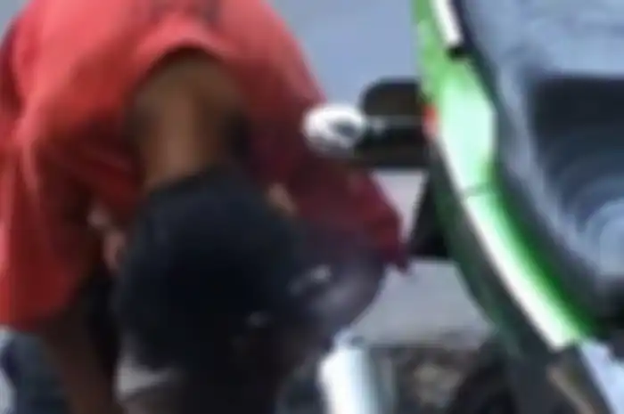 Seorang bocah terlihat mengeringkan rambut dengan asap knalpot motor 2-tak