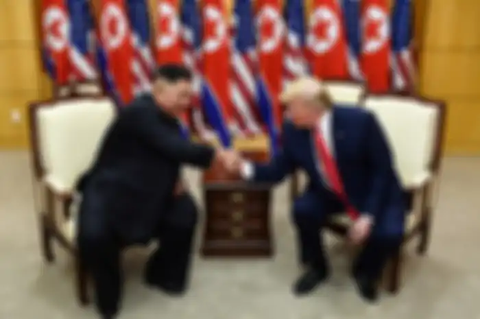 Pemimpin Korea Utara Kim Jong Un (kiri) dan Presiden AS Donald Trump berjabat tangan dalam sebuah pertemuan di wilayah keamanan bersama (JSA) Panmunjom di zona demiliterisasi (DMZ) Korea, Minggu (30/6/2019). Kedatangan Trump ke zona demiliterisasi Korea awalnya diagendakan untuk pertemuan dengan Pre