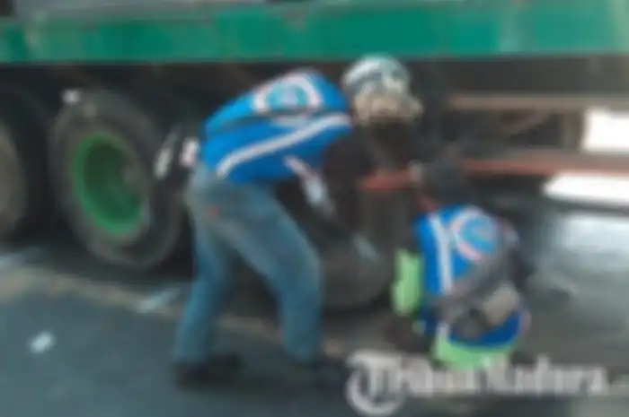 Sebuah truk kontainer diperiksa bagian bawahnya oleh relawan kecelekaan setelah melindas tiga pengendara vario di Mojokerto, Senin (1/7/2019)