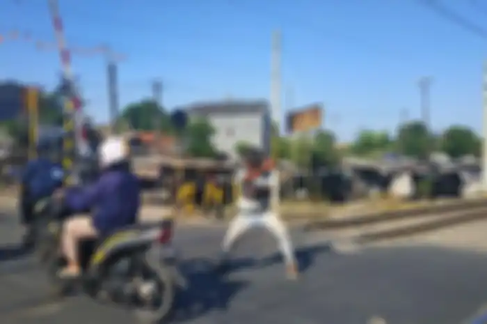 Diryan, mengatur lalu lintas di perlintasan kereta sambil mempraktekan jurus silatnya