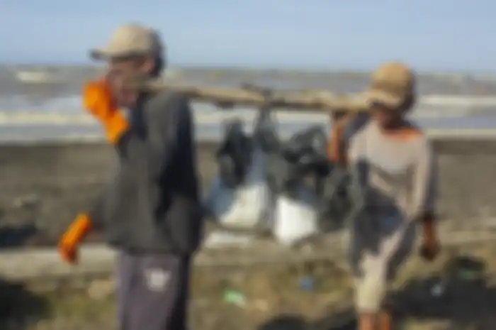 Warga membawa karung berisi pasir yang tercemar tumpahan minyak mentah (Oil Spill) di pesisir Pantai Cemarajaya, Karawang, Jawa Barat, Rabu (24/7/2019). Karung berisi pasir yang tercemar minyak mentah tersebut dikumpulkan dan akan dipindahkan ke lokasi penyimpanan limbah B3 (Bahan Berbahaya dan Bera