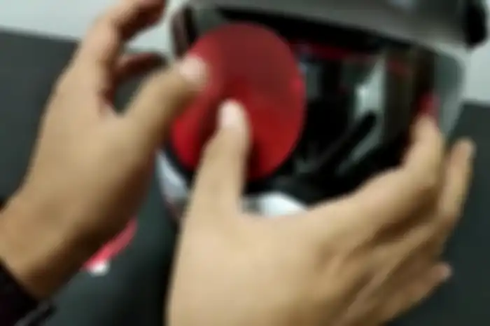 Proses menempelkan stiker film anti air di kaca helm
