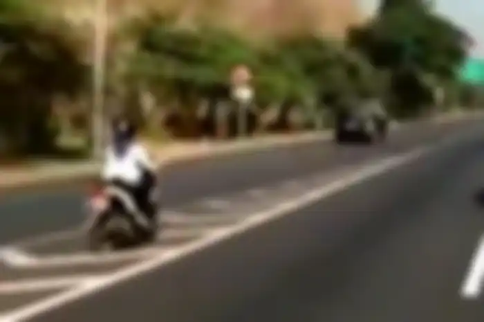 Honda Beat melintasi jalan tol di Surabaya yang mengarah ke Kota Satelit dan Gresik.