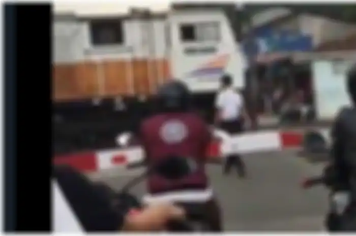 Petugas pria berjalan menuju lokomotif yang kebetulan berhenti di tengah rel persimpangan kereta api.