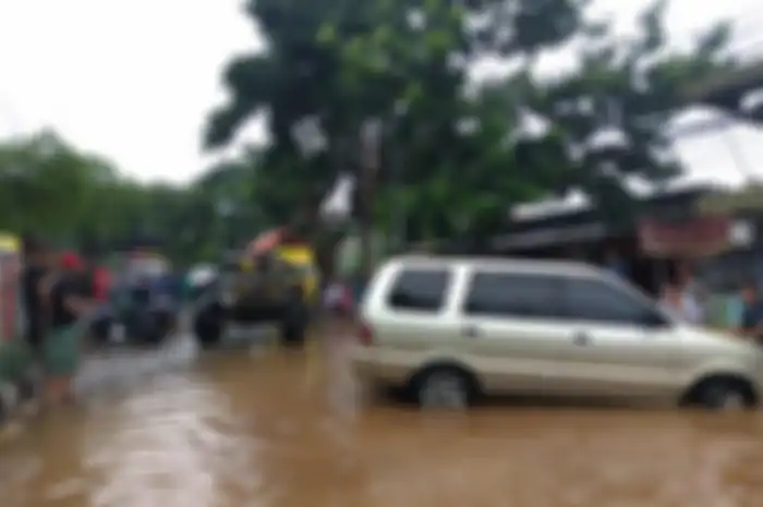 Mobil Jeep lawas tahun 1952 menarik sebuah Isuzu Panther keluar dari rendaman banjir.