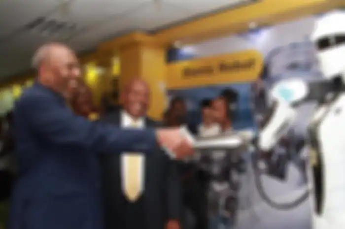 Perdana Menteri Uganda, Ruhakana Rugunda, berjabat tangan dengan robot yang dikontrol lewat 5G.