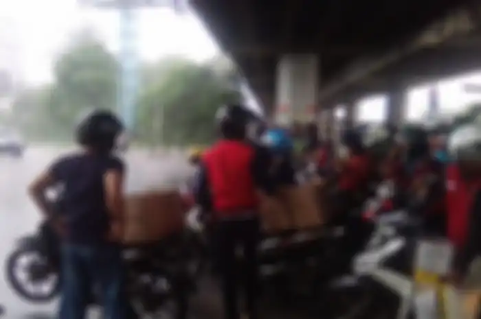 Walaupun sudah ada larangan, banyak pemotor yang masih nekat berteduh di kolong tol atau flyover saat hujan.