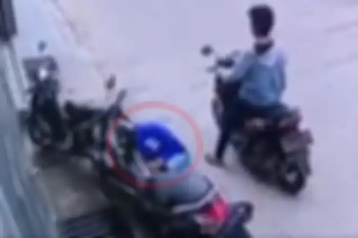 Maling Yamaha NMAX jongkok di depan dek kanan untuk mencari kabel kunci kontak