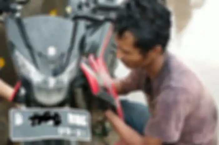 Seorang montir dadakan terlihat sedang bantu motor yang mogok akibat banjir