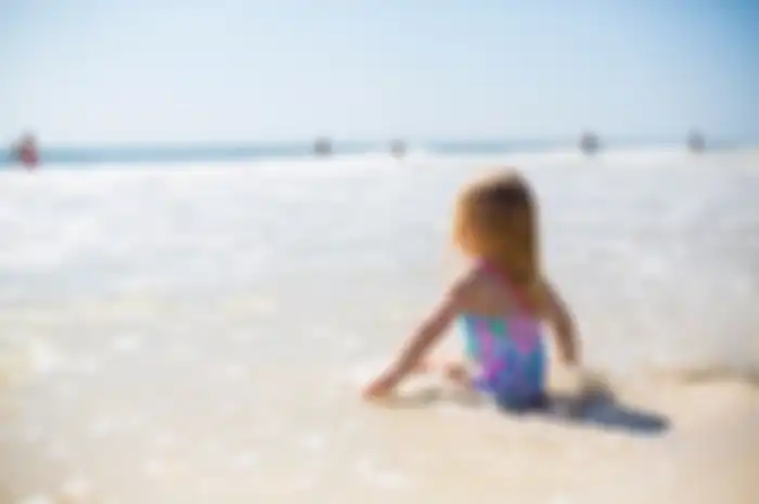 Seorang anak kecil berjemur di pantai.