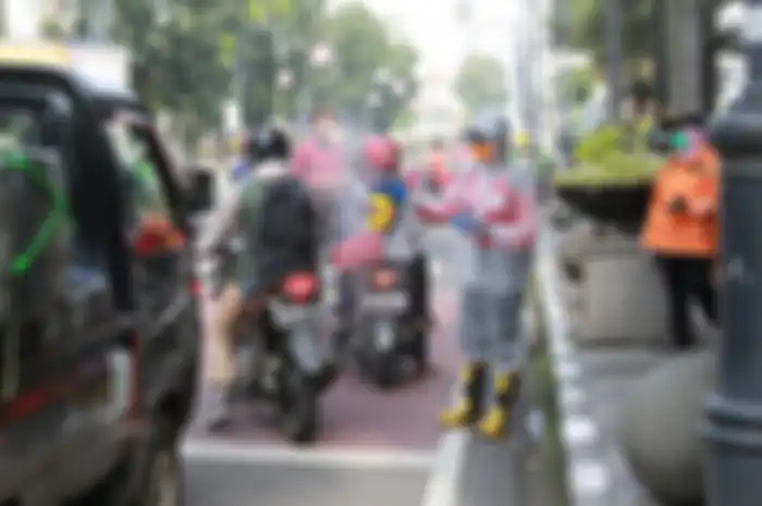  Srikandi Damkar Bandung sedang menyemprotkan cairan disinfektan kepada para pengendara kendaraan bermotor di Jalan Asia Afrika, Kota Bandung