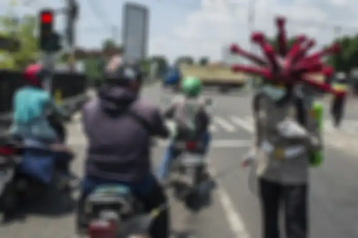 Anggota polisi memakai helm berbentuk virus corona melakukan imbauan dan penyemprotan cairan disinfektan pada kendaraan di jalanan di daerah Mojokerto, Jawa Timur, Jumat (3/4/2020). Cara unik ini dilakukan oleh sejumlah anggota dari Polres Mojokerto dalam upaya menekan penyebaran virus corona