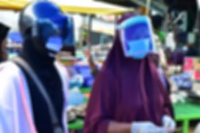 Dua perempuan mengenakan pelindung wajah sebagai tindakan pencegahan terhadap penyebaran virus corona (Covid-19), saat membeli makanan laut di pasar pagi di provinsi Narathiwat, Thailand selatan, Jumat (3/4/2020).