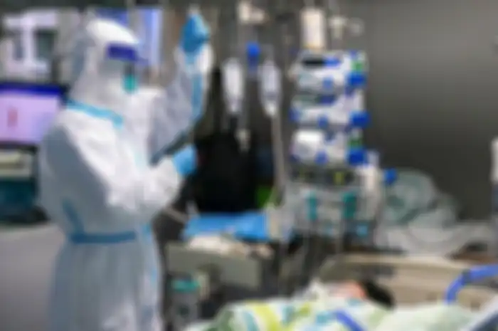 Pasien dengan ventilator dan tenaga medis.