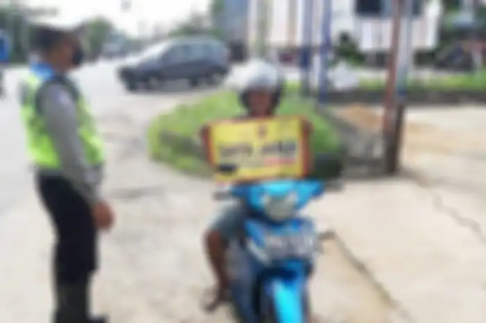 Pengendara motor pakai spanduk 
