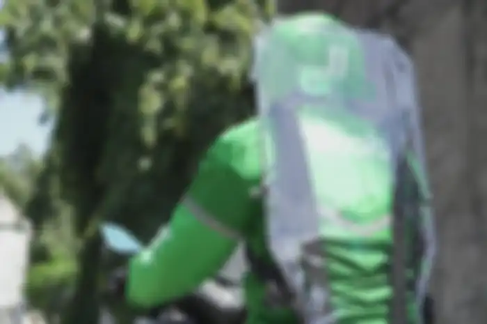 Pengemudi Ojek Online menggunakan partisipasi pembatas berbahan plastik untuk mengurangi kontak fisik dengan penumpang.