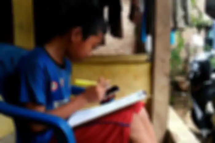 Jonathan (13) pelajar SMP di Bandar Lampung sedang memahami soal dari pembelajaran daring kelasnya, Kamis (6/8/2020). Untuk memenuhi kebutuhan kuota internet, Jonathan berjualan pempek di sekitar kampung.