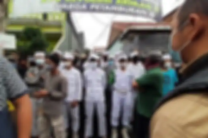 Sejumlah orang berpakain putih menghalang-halangi polisi yang hendak menyampaikan surat pemanggilan kepada Rizieq Shihab di Petamburan, Minggu (29/11/2020) sore. 