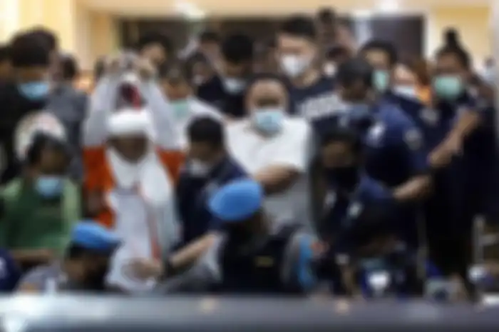 Pemimpin Front Pembela Islam (FPI) Muhammad Rizieq Shihab mengenakan baju tahanan seusai menjalani pemeriksaan di Polda Metro Jaya, Jakarta Pusat, Minggu (13/12/2020) dini hari. 