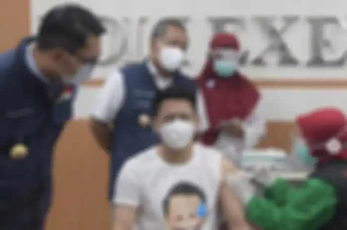 Gubernur Jawa Barat Ridwan Kamil (kiri) menyaksikan penyanyi Ariel NOAH menjalani vaksinasi Covid-19 di Kota Bandung, Kamis (14/1/2021).