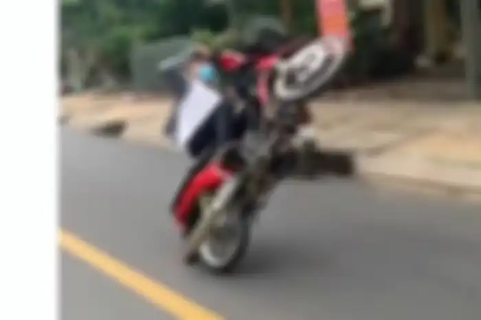 Ilustrasi Pemotor atraksi wheelie di jalan raya