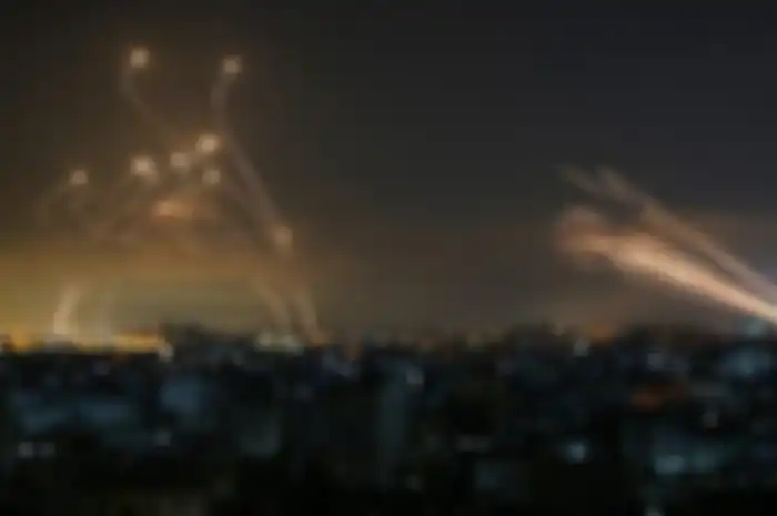 Roket dari Gaza, di sebelah kanan, terlihat di langit malam yang ditembakkan ke arah Israel dari Beit Lahia di Jalur Gaza utara pada 14 Mei 2021, sementara rudal pencegat Iron Dome, di sebelah kiri, bangkit untuk menghadang mereka.