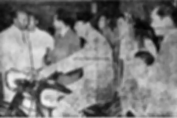 Foto Presiden Soekarno duduk di atas sebuah motor klasik.