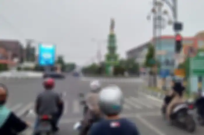 Ilustrasi menurunkan kaki saat motor berhenti di persimpangan jalan.