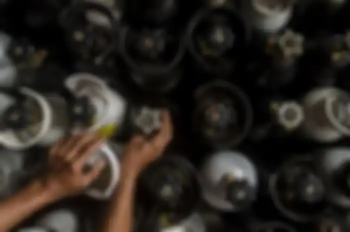 Pedagang yang menata tabung gas oksigen untuk dijual