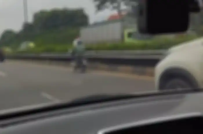 Viral pemotor Honda Supra berbaju loreng masuk jalan tol di jalur cepat, diduga menggunakan plat nomor bodong.