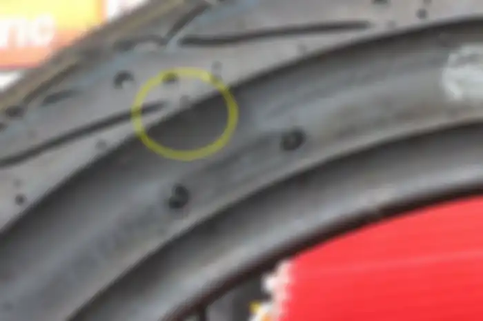 tanda segi tiga TWI (Tread Wear Indicator) pada dinding ban motor.