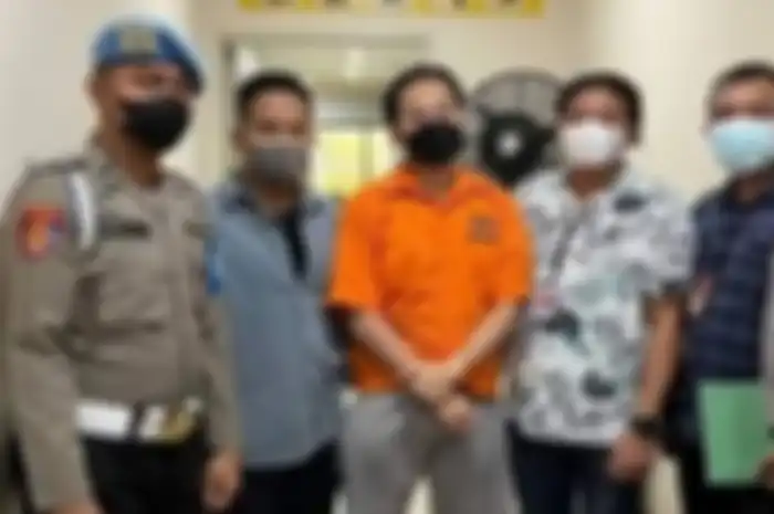 Indra Kenz memakai baju oranye.
