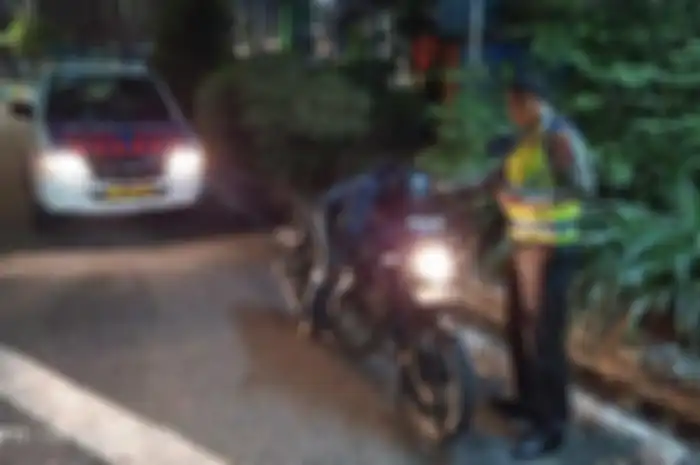 Karena kecapekan keliling kota, seorang pemotor ketiduran di atas motor Yamaha V-ixion dengan kondisi mesin masih menyala.