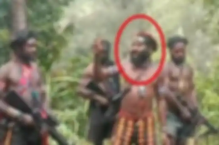 Tanpa mengenakan baju, Oni Kobagau berpidato dan didengarkan beberapa anggota KKB Papua yang menenteng senjata api. 
