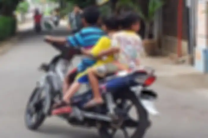 ilustrasi anak di bawah umur yang mengendarai motor berbonceng tiga tanpa menggunakan helm.