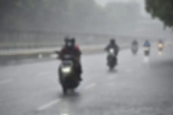 Foto ilustrasi naik motor di tengah hujan. Badai dahsyat hingga hujan ekstrem bakal melanda Jabodetabek 28 Desember 2022 besok.
