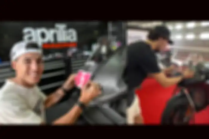 Pembalap MotoGP Aleix Espargaro (kiri) dan Alex Rins melakukan ritual pasang stiker nomor start sendiri di motor barunya, percaya tak percaya biar lebih akrab demi dongkrak performa