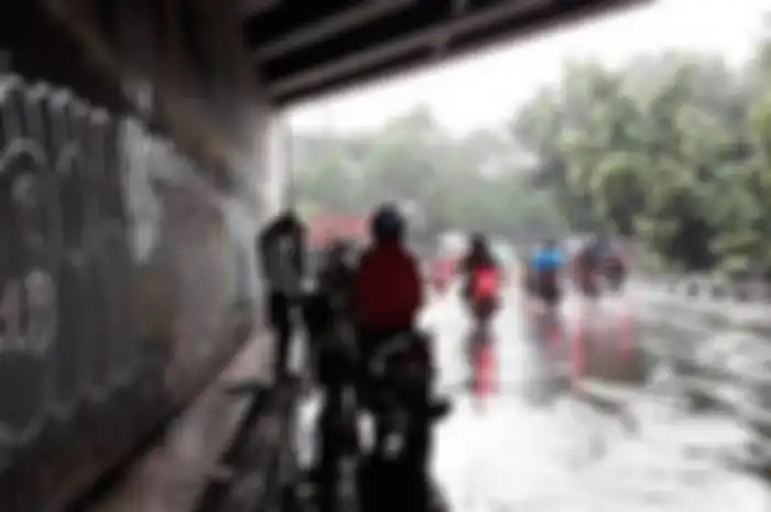 Ilustrasi pemotor berteduh di underpass saat hujan.