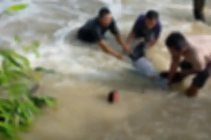 Seorang petugas Dishub terseret banjir luapan kali Lamong di jalan raya Benjeng, Selasa (10/6/2025). Korban selamat berhasil ditolong warga, sementara motornya belum ditemukan. 
