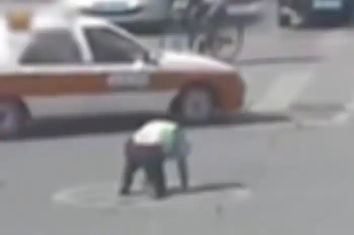 Seorang polisi di China tersungkur di aspal saat bertugas.