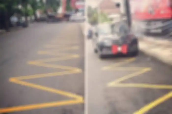 Marka garis kuning bergerigi (Embargo Parkir), sebagai tanda dilarang berhenti ataupun parkir.