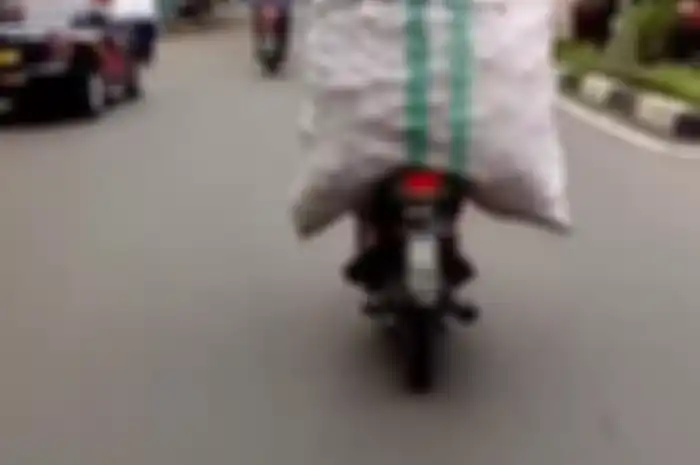 Seorang pengendara motor bawa karung setinggi monas, hebat bisa enggak jatuh.
