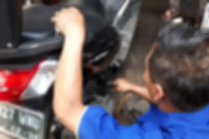 Ilustrasi mekanik semprot angin ke mesin saat ganti oli motor.