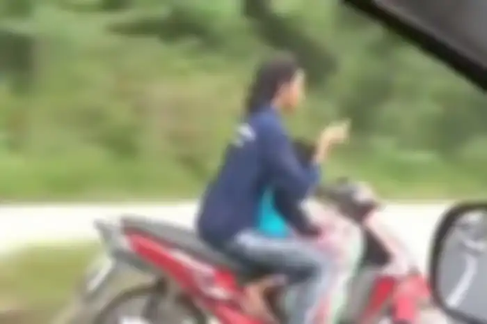 Perempuan nekat lepas setang sambil main ponsel, padahal sangat berbahaya.