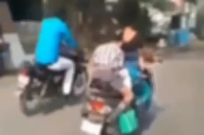 Seorang anak dibonceng sambil bikin tugas sekolah, bahaya banget.