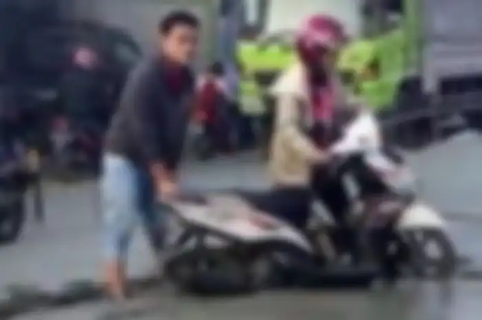 Terlihat dalam foto pengendara seperti seorang ibu yang tengah dibantu seorang pria untuk mengeluarkan motornya