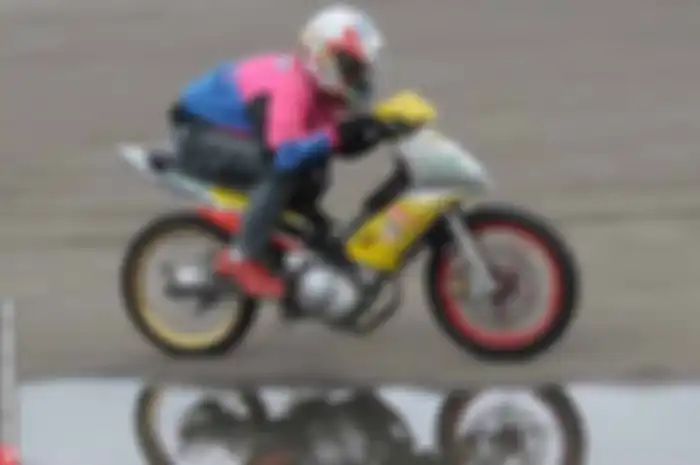 Judul di atas bukan merujuk fisik pembalapnya yang kidal, namun karena penggunaan knalpot yang beda dari peserta lainnya. Kalau pada umumnya knalpot motor itu nongol di sebelah kanan, nah, motor andalan bengkel 59 Gass yang ngendon di Jl. Gudang Air 