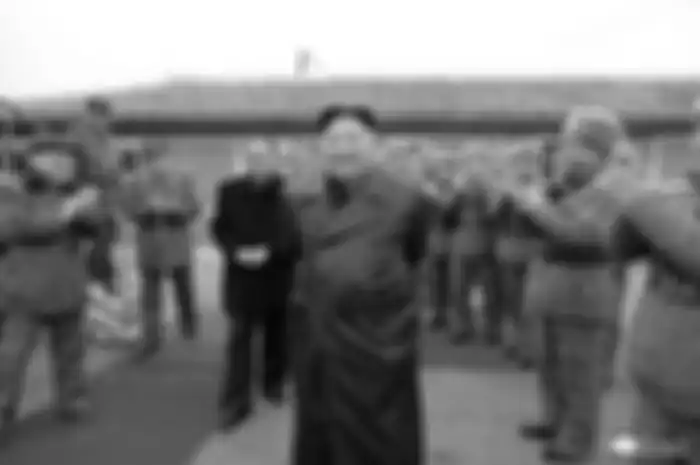 Gambar tak bertanggal yang dirilis kantor berita Korea Utara, KCNA, pada 29 November 2019 memperlihatkan Kim Jong Un mengawasi uji coba senjata terbaru. Kim yang mengenakan jubah warna hitam tersenyum dengan pasukan Korea Utara di sekelilingnya memberikan tepuk tangan.