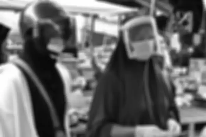 Dua perempuan mengenakan pelindung wajah sebagai tindakan pencegahan terhadap penyebaran virus corona (Covid-19), saat membeli makanan laut di pasar pagi di provinsi Narathiwat, Thailand selatan, Jumat (3/4/2020).